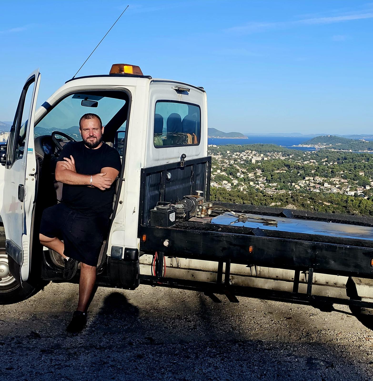 Marc Le Gall devant son camion plateau, la rade de Toulon en arrière-plan